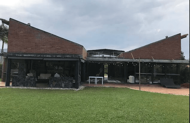 Casa Parcelación Andalucía - Fachada en ladrillo a la vista con terraza cubierta y jardín, Rionegro