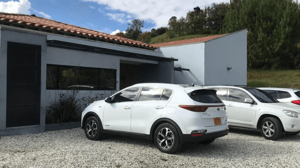 Casa Campestre El Retiro - Fachada con muros blancos, techo de teja de barro y parqueadero en gravilla