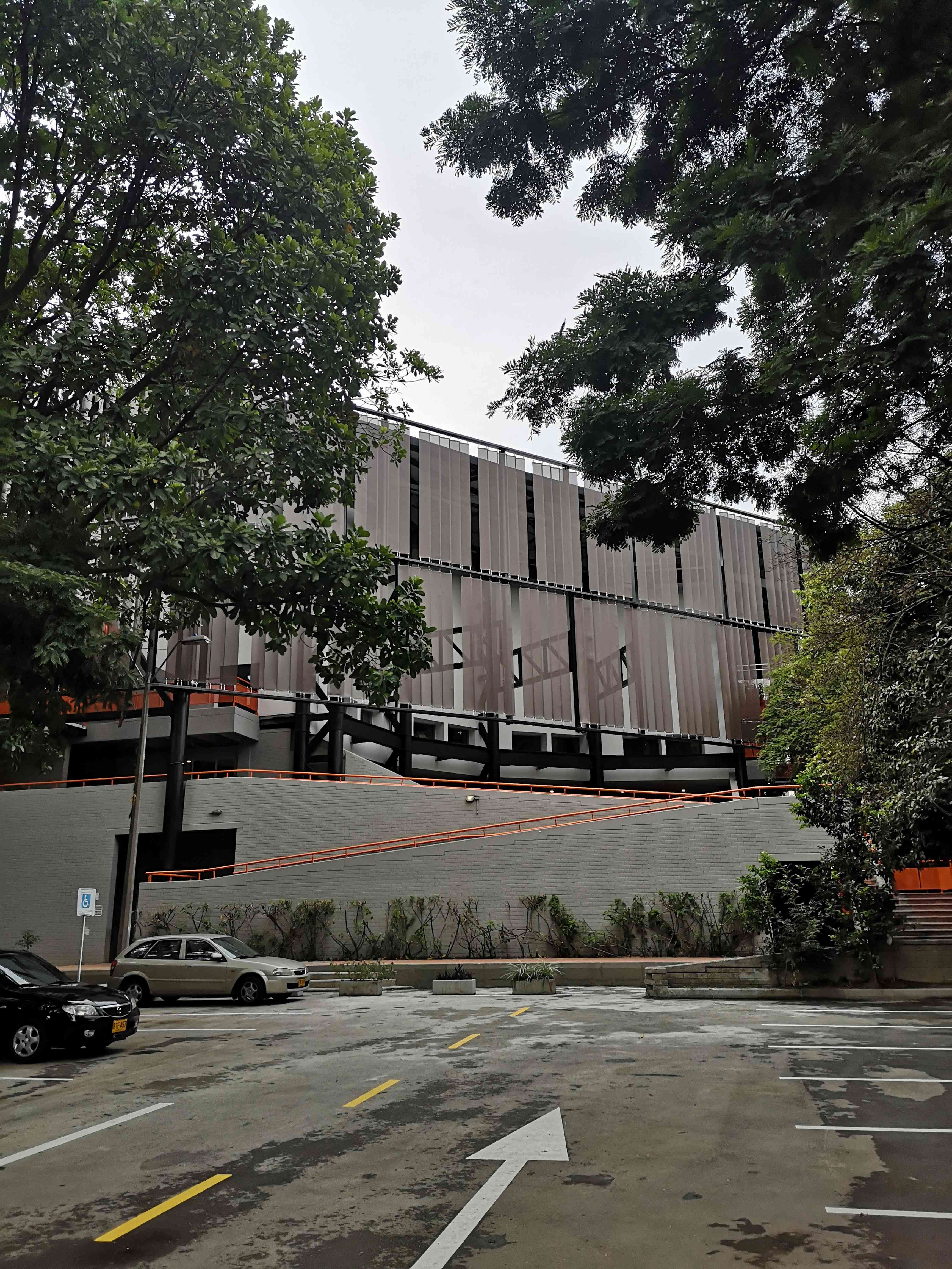 Universidad Nacional Bloque 12 - Edificio terminado con fachada de paneles y barandas naranjas